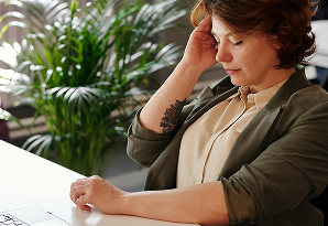 Mujer sentada en un escritorio, concentrada en su trabajo con una computadora portátil frente a ella.
