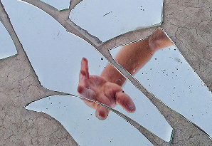 Una mano extendiéndose para tocar la superficie de un espejo