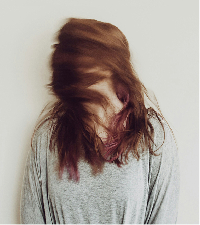 Mujer de cabello largo, mirando hacia un lado, con una expresión serena en un entorno natural