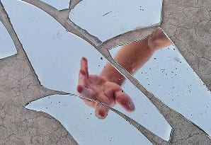 Una mano extendiéndose para tocar la superficie de un espejo